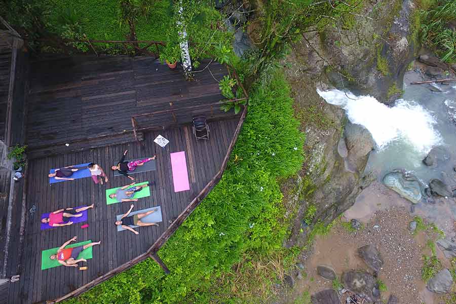 Guests at the Rios Lodge enjoy yoga on the front porch overlooking the Pacuare River